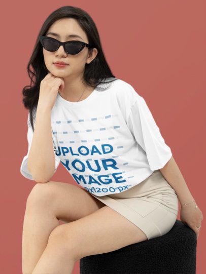 Oversized T-Shirt Mockup of a Woman with Sunglasses Posing in a Studio