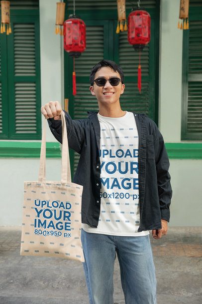 Oversized T-Shirt Mockup Featuring a Happy Man Showing a Tote Bag in a Lunar New Year Celebration m52232