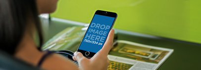 Mockup of a Woman Reading a Magazine and Using an iPhone 6