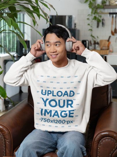 Sweatshirt Mockup of a Man Sitting on a Couch at Home while Listening to Music m52240