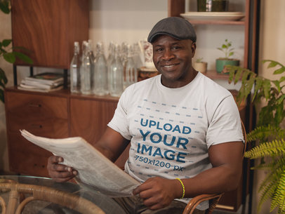 Mockup of a Smiling Man Wearing a Round Neck T-Shirt Reading the Newspaper