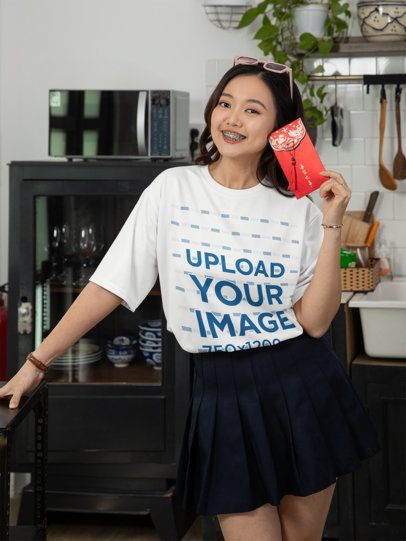 Chinese New Year-Themed T-Shirt Mockup of a Smiling Woman Holding a Red Envelope at Home m52251