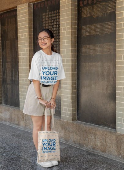 Lunar Year-Themed T-Shirt Mockup of a Joyful Woman Holding a Tote Bag on the Street