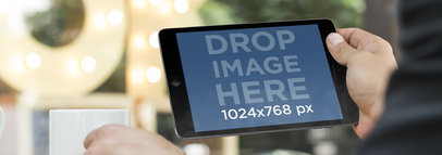 Young Man Using iPad Mini at a Coffee Shop Mockup Template