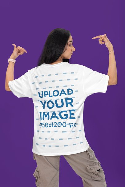 Back-View Mockup of a Woman Pointing at Her Oversized T-Shirt in a Studio
