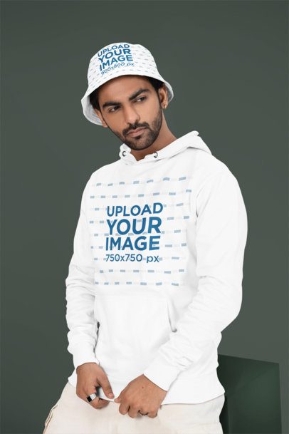 Pullover Hoodie Mockup Featuring a Bearded Man Posing in a Studio With a Sublimated Bucket Hat