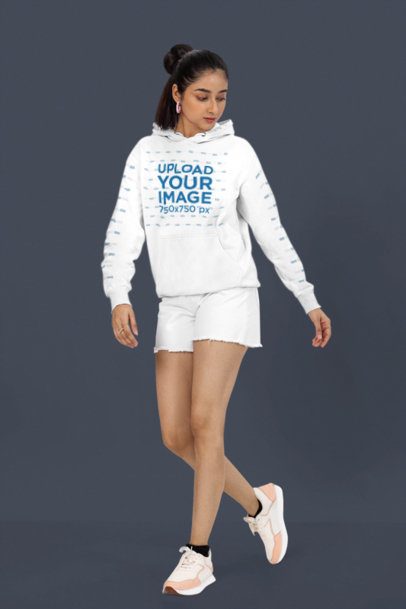 Pullover Hoodie Mockup Featuring a Woman Walking in a Studio With a Serious Look