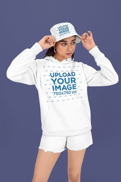 Hoodie Mockup of a Serious Woman Wearing a Sublimated Bucket Hat in a Studio