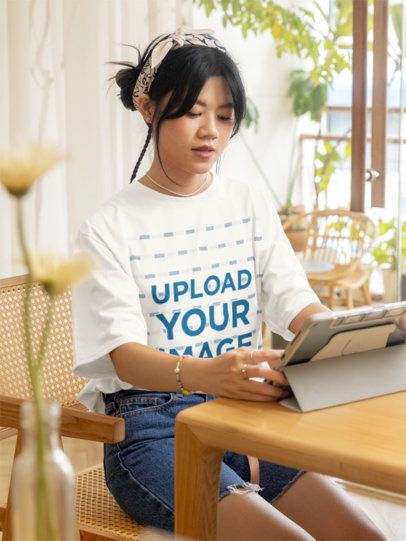Oversized T-Shirt Mockup Featuring a Teenage Girl Looking at a Tablet m51467