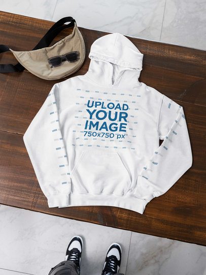 POV-Themed Mockup Featuring a Gildan Hoodie With Customizable Sleeves Lying on a Wooden Table