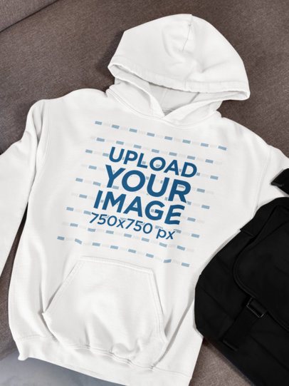 Gildan Mockup Featuring a Pullover Hoodie Placed on a Couch With a Bag