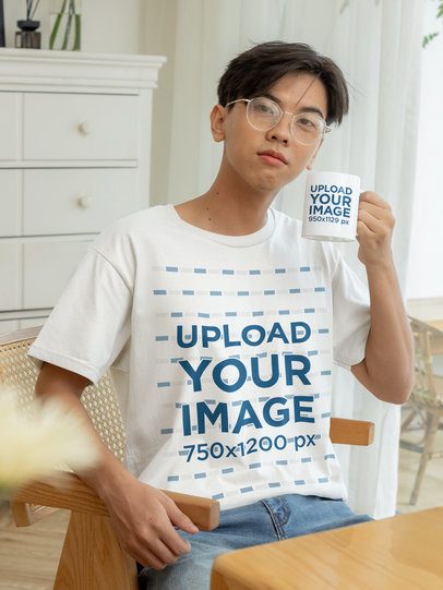 Round-Neck Tee Mockup of a Teenage Boy Holding a Coffee Mug in a Room
