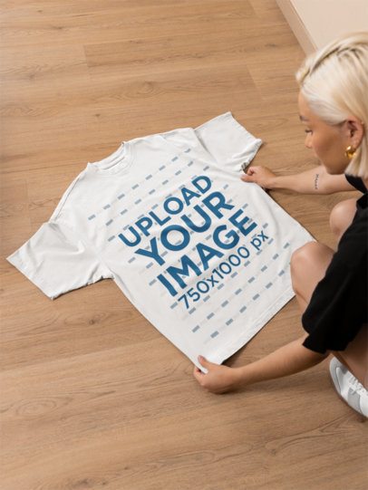 Mockup of a Woman Putting an Oversized Round-Neck T-Shirt on the Floor