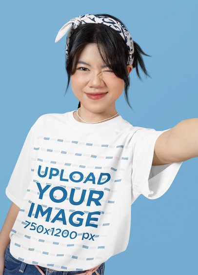 Oversized T-Shirt Mockup of a Girl Winking While Taking a Selfie in a Studio