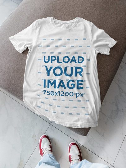 Bella Canvas Mockup Featuring a Man Looking at a Round-Neck T-Shirt Lying on a Couch m52025