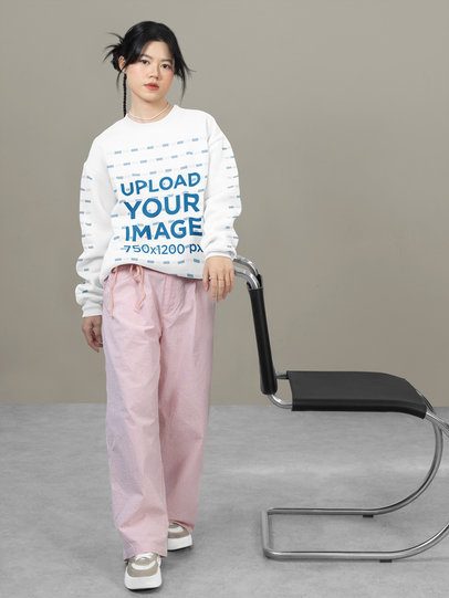 Sweatshirt Mockup of a Serious Teenage Girl Posing Against a Customizable Wall
