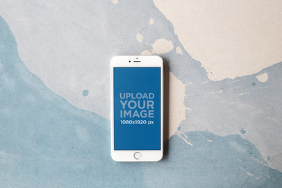 Silver iPhone Mockup Featuring a Cream Paint Stain on a Soft Blue Surface a21616