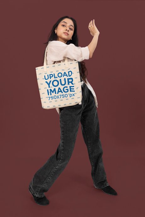 Tote Bag Mockup Featuring a Woman Posing With a Serious Look in a Studio