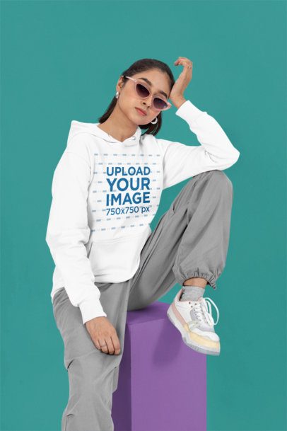 Pullover Hoodie Mockup of a Woman Sitting on a Cube While Wearing Sunglasses m53089