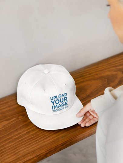 Mockup of a Woman Putting a Snapback Hat on a Wooden Shelf