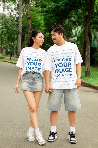 Oversized T-Shirt Mockup Featuring a Happy Man and a Woman Holding Hands in the Park