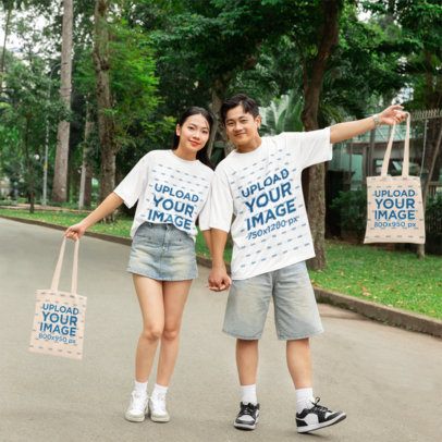 Oversized T-Shirt Mockup Featuring a Happy Couple Posing With Their Tote Bags in a Park