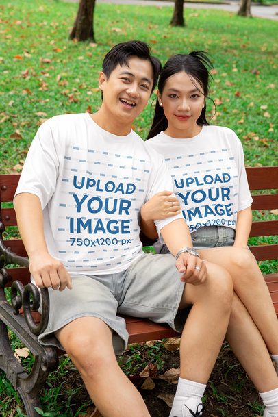 Oversized T-Shirt Mockup of a Happy Couple Sitting on a Bench in the Park for Valentine's Day m53737