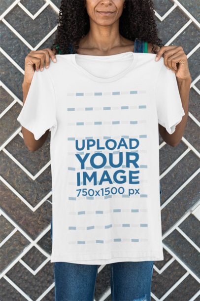 Mockup of a Cropped-Face Smiling Woman Holding a Bella Canvas T-Shirt Against a Wall m51768