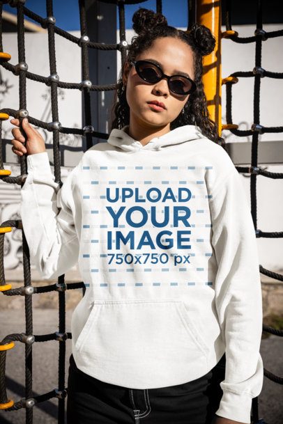 Comfort Colors Hoodie Mockup Featuring a Woman With Sunglasses Posing in a Playground m53351