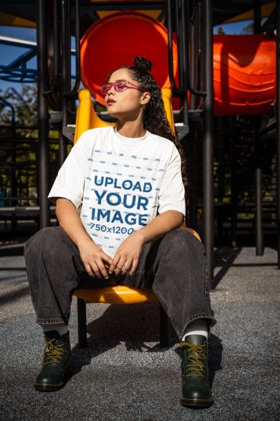 Oversized T-Shirt Mockup of a Woman Sitting on a Playground Slider