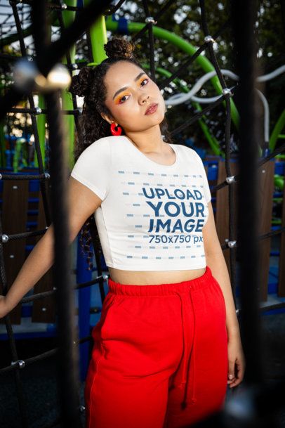 Bella Canvas Crop Top Mockup Featuring a Woman With Graphic Eye Makeup Posing in a Playground m53364