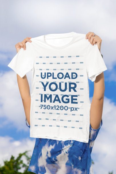 Bella Canvas Mockup Featuring a Person Holding a T-Shirt Against the Sky