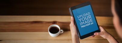 Mockup of a Woman Using a Black iPad Mini While Drinking Coffee 