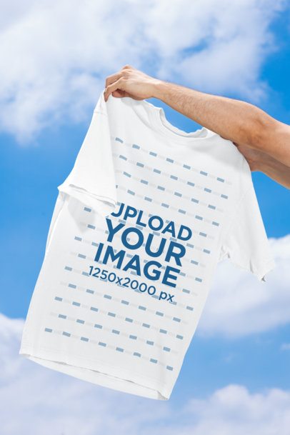 Oversized T-Shirt Mockup Featuring a Pair of Hands Holding a Garment Against the Sky