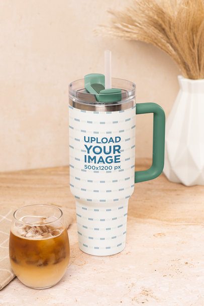 Mockup of a Stanley Tumbler Placed Next to an Ice Coffee in a Kitchen Table