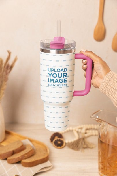 Mockup of a Woman Holding a Stanley Tumbler Against a Table With Food