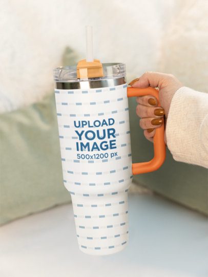 Mockup of a Woman Holding a Sublimated Stanley Tumbler in a Cozy Setting