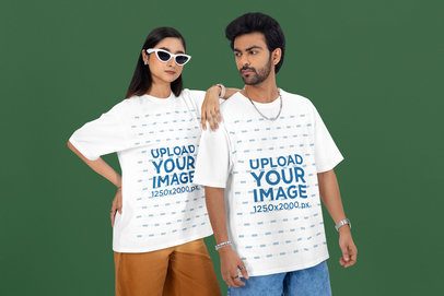 Oversized T-Shirt Mockup of a Woman With Sunglasses Posing With a Serious Man in a Studio