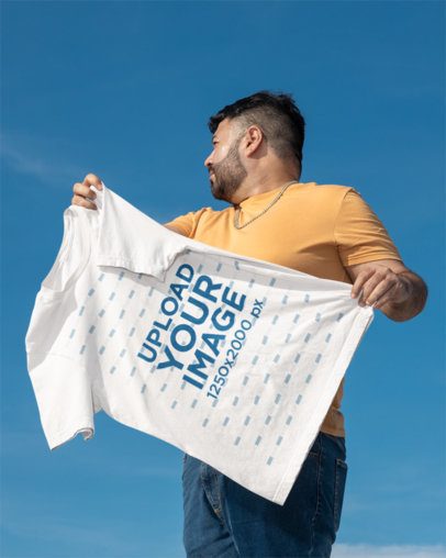 Bella Canvas Mockup Featuring a Man Holding a Round-Neck T-Shirt Against the Sky