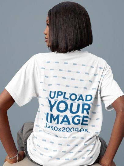 Back-View T-Shirt Mockup of a Woman in Dark Jeans Sitting in a Studio m54118