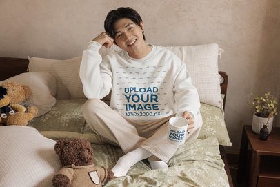 Sweatshirt Mockup Featuring a Happy Man Holding a Coffee Mug While Sitting on a Cozy Bed