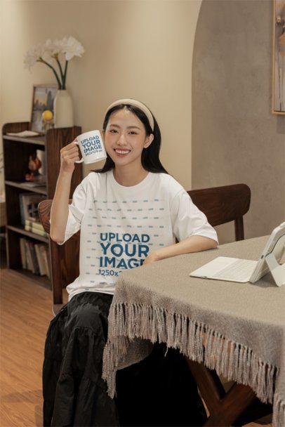 Oversized Tee Mockup of a Joyful Woman Posing in a Cozy Room With a Coffee Mug