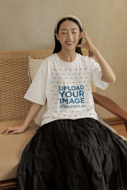 Oversized T-Shirt Mockup Featuring a Cheerful Woman Sitting in a Cozy Couch