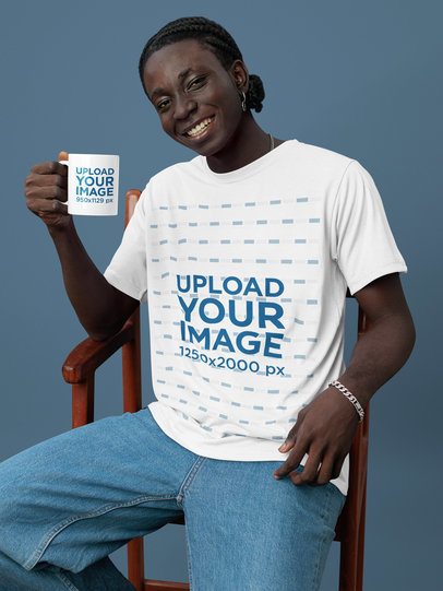 Coffee Mug Mockup of a Cheerful Man Wearing a T-Shirt While Sitting on a Chair in a Studio