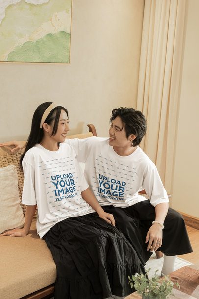 Oversized T-Shirt Mockup Featuring a Cheerful Couple Sitting in a Cozy Couch