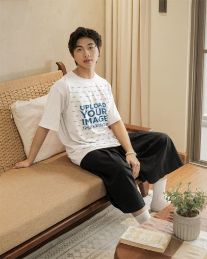 Oversized T-Shirt Mockup of a Serious Man Sitting on a Cozy Couch