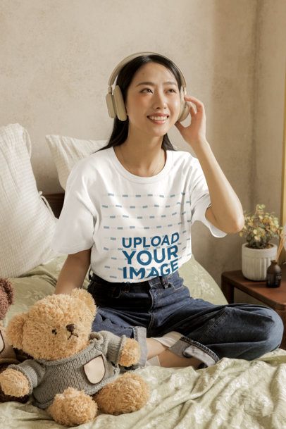 T-Shirt Mockup Featuring a Smiling Woman With Headphones Posing in a Cozy Setting m54385