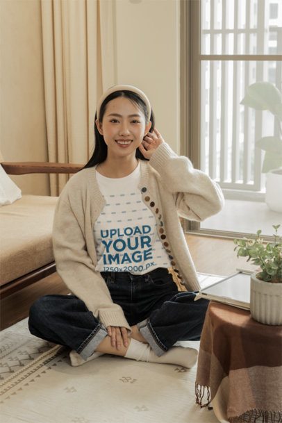 Oversized T-Shirt Mockup of a Cheerful Woman Sitting on the Floor in a Cozy Living Room