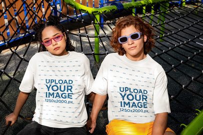 Oversized T-Shirt Mockup of a Man and a Woman Posing on a Playground Net