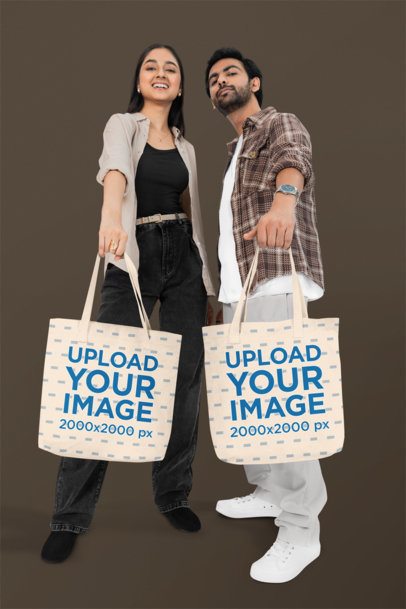 Mockup of a Cheerful Couple Showing Their Tote Bags in a Studio